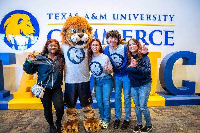 Four students pose with Lucky the Lion mascot.
