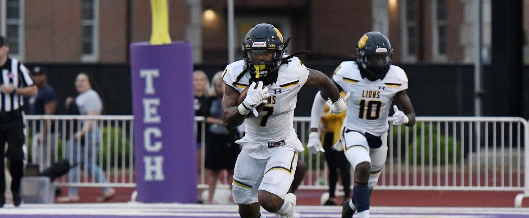 Two football players run down the field.