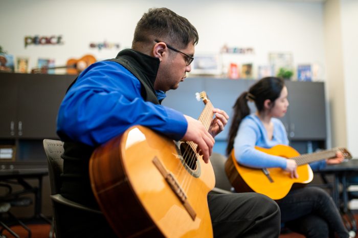 A male student playing the guitar.