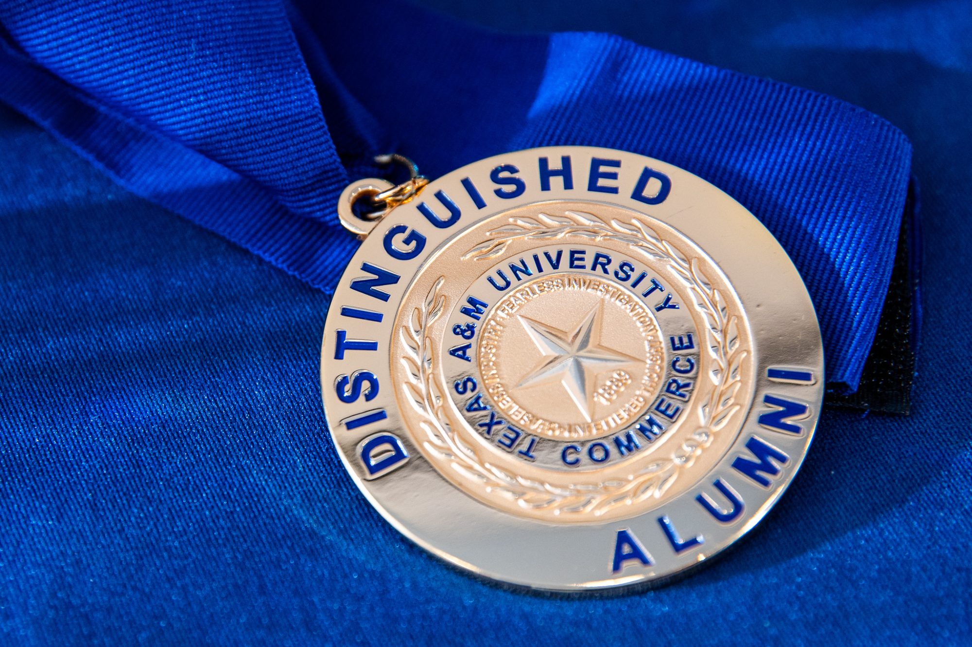 Distinguished Alumni medal lies on blue background.
