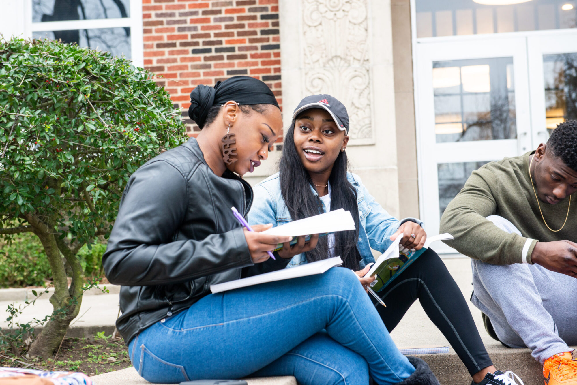 Two female student outside a building completing a school assignment.