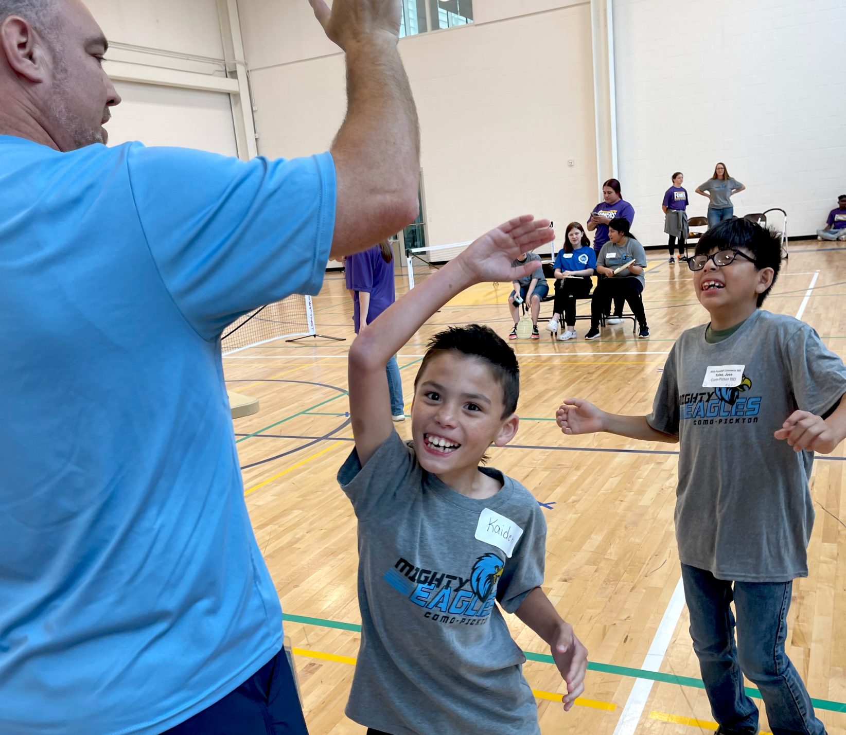 Two Special Olympics athletes celebrate while one athlete high-fives an attendee.