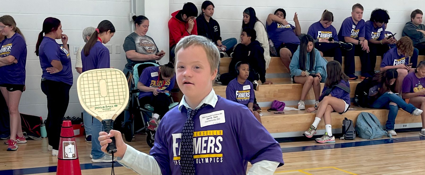 A Special Olympics athlete holds a pickleball paddle in mid-swing.