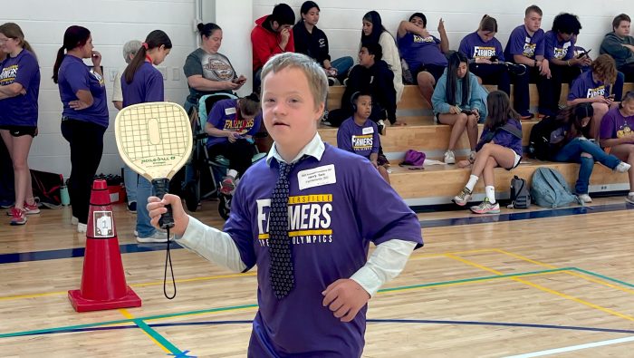 A Special Olympics athlete holds a pickleball paddle in mid-swing.