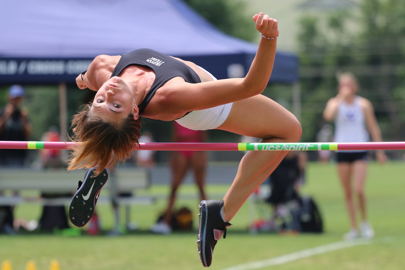 A female athlete competing in the high jump event clears the bar.