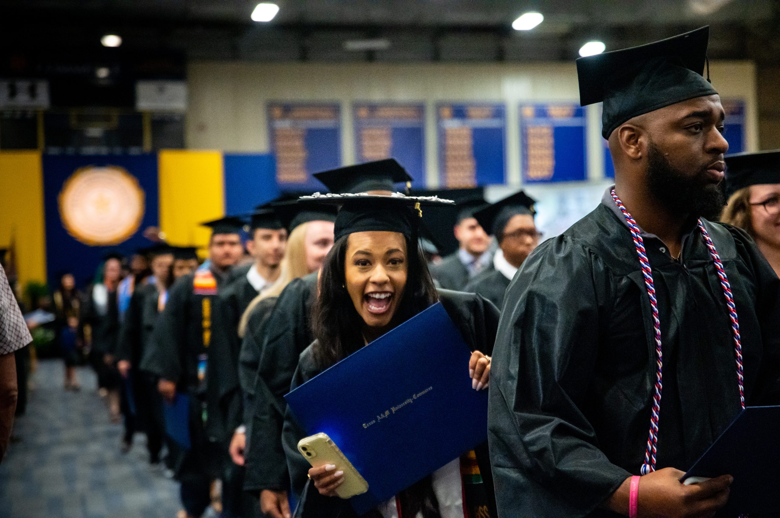 A female student graduating and smiling at the camera man.