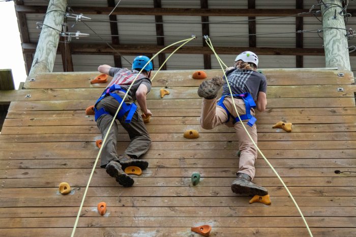 Two students climbing up a board.