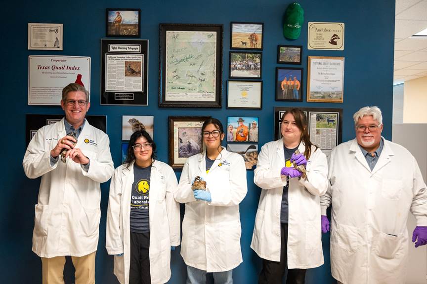 A group of faculty and student holding quail birds in there hand while smiling.