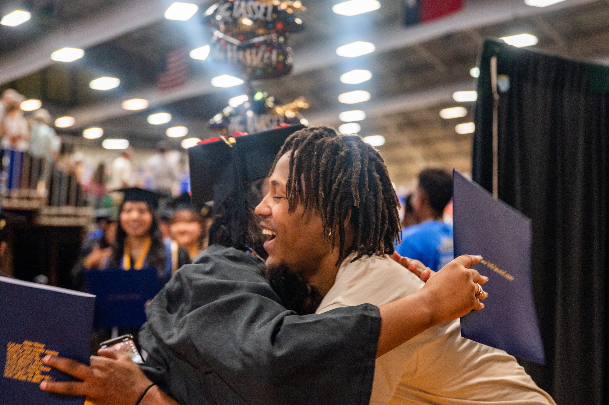 A student graduating and being hug by someone they know.