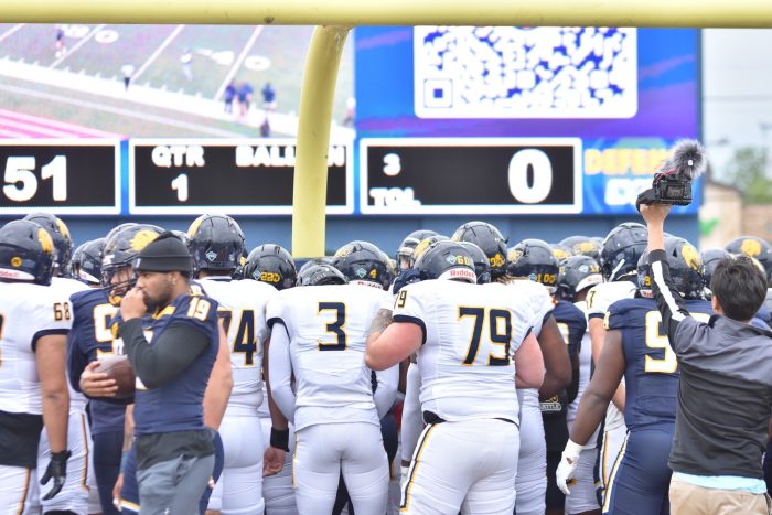 A group of football players around the goal post.