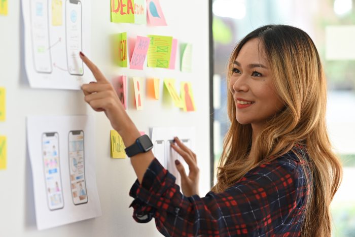 A female student pointing to something on a white board and explaining it.