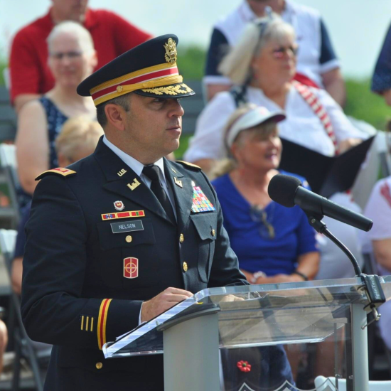 A member of the U.S. military speaks at a podium in their dress uniform.
