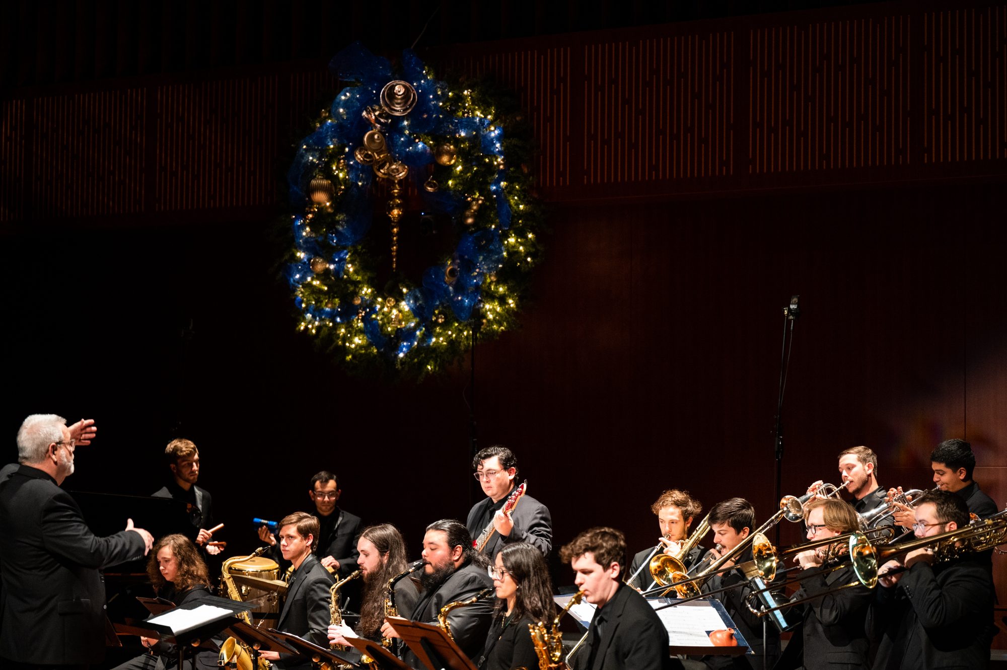 A musical band playing under a large garland wreath.