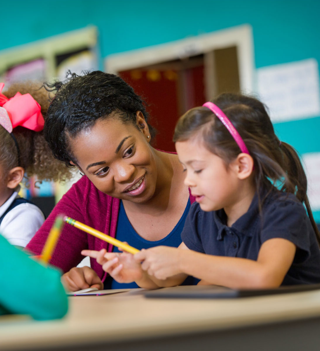 A student teacher is showing a student how to complete school work.