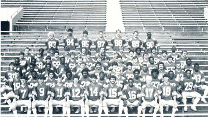 Black and white photo of football team sitting down.