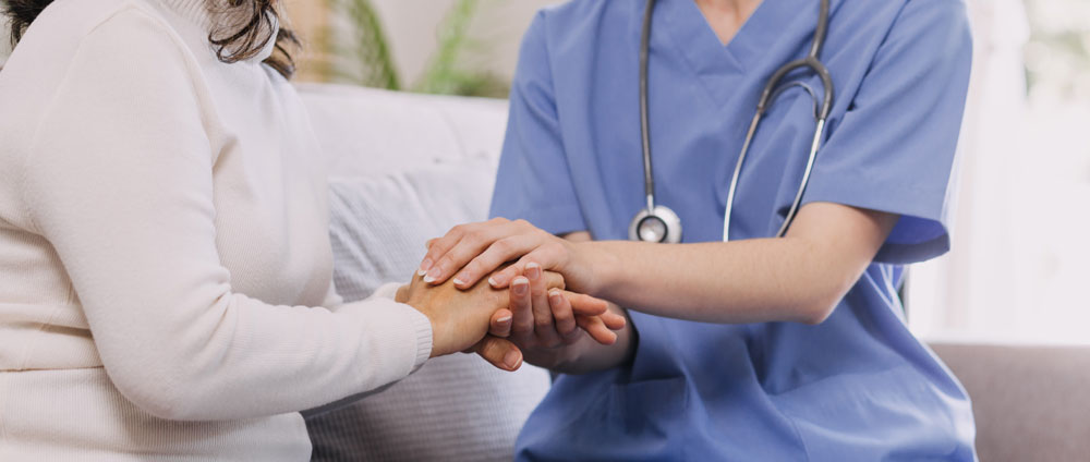 A nurse holding a patients hand to check vitals.