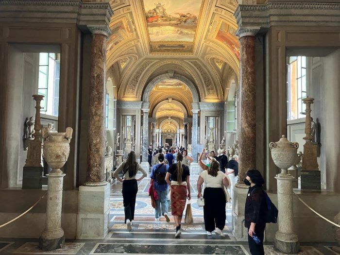 A group of individuals randomly walking in a museum in Italy.