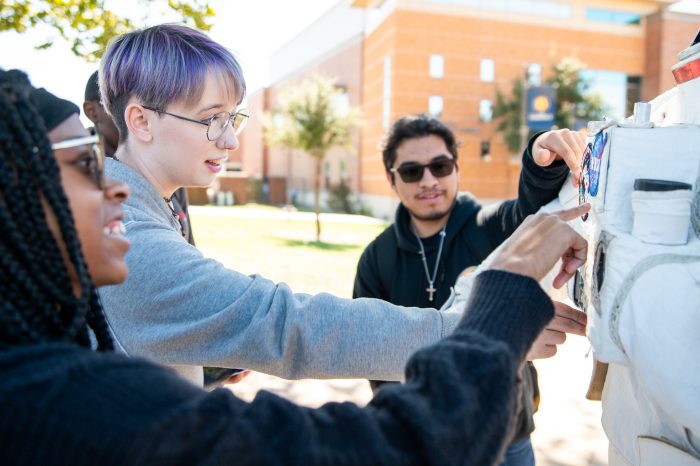 Three students examine NASA astronaut suit