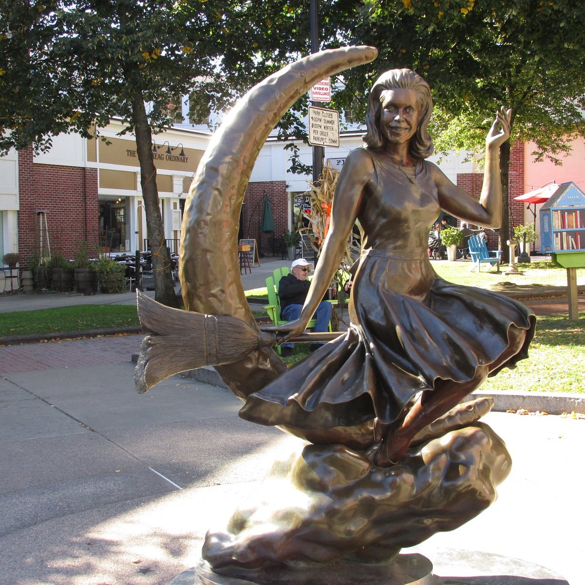 A bronze statue of a woman riding a broom in front of a crescent moon
