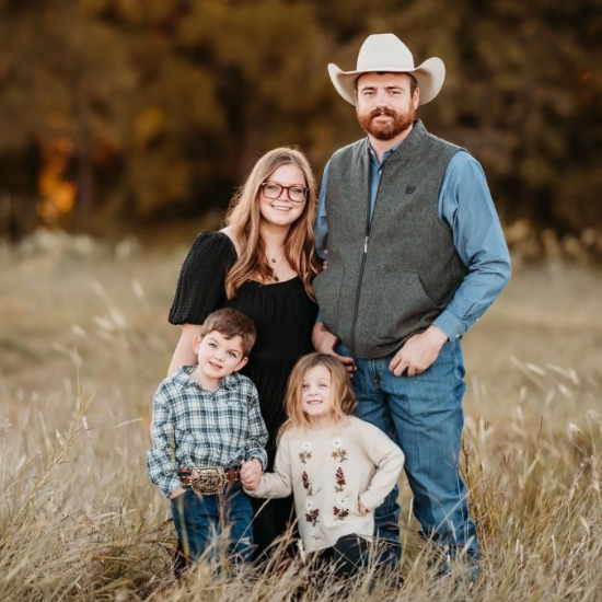 A family of four takes a photo in a field.