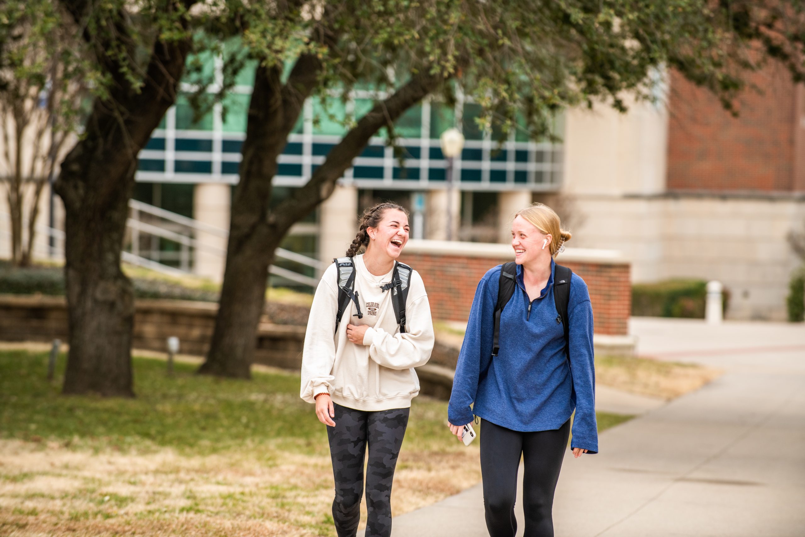 Two female students walking and speaking outside.