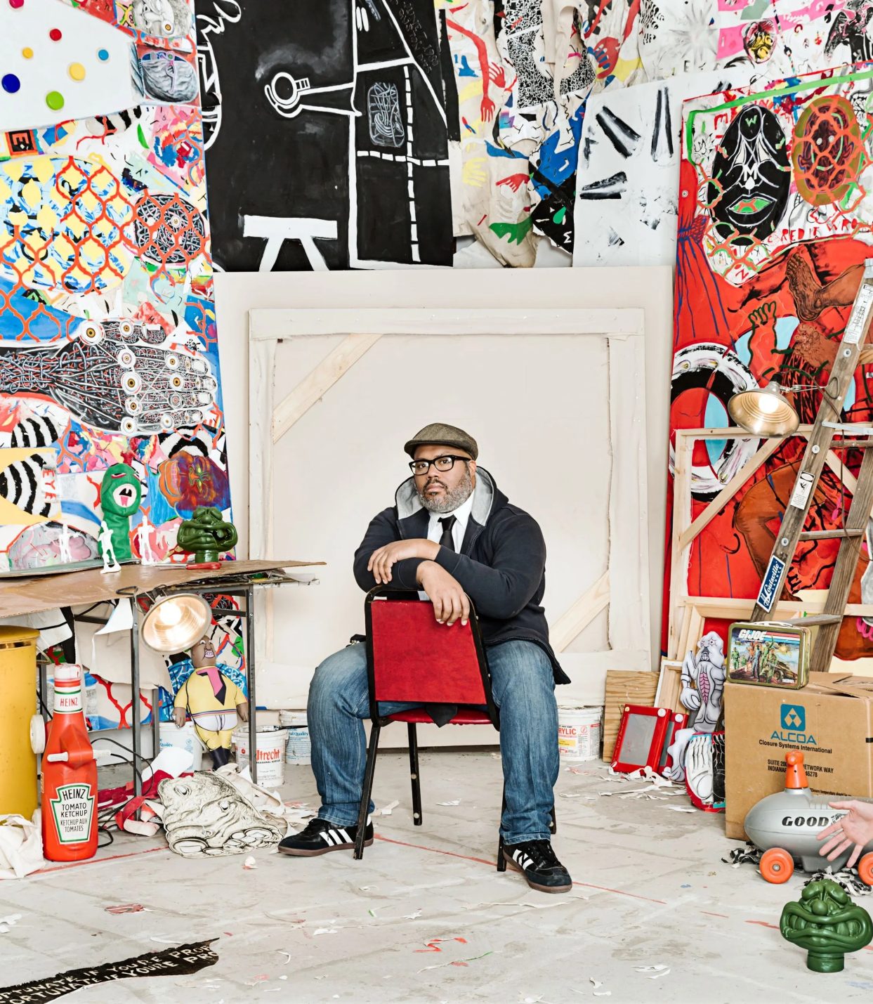 Trenton Doyle Hancock sitting in a chair surrounded by colorfully painted walls