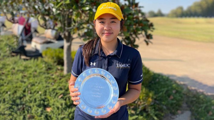 Golfer smiles at camera while holding a silver commemorative plate