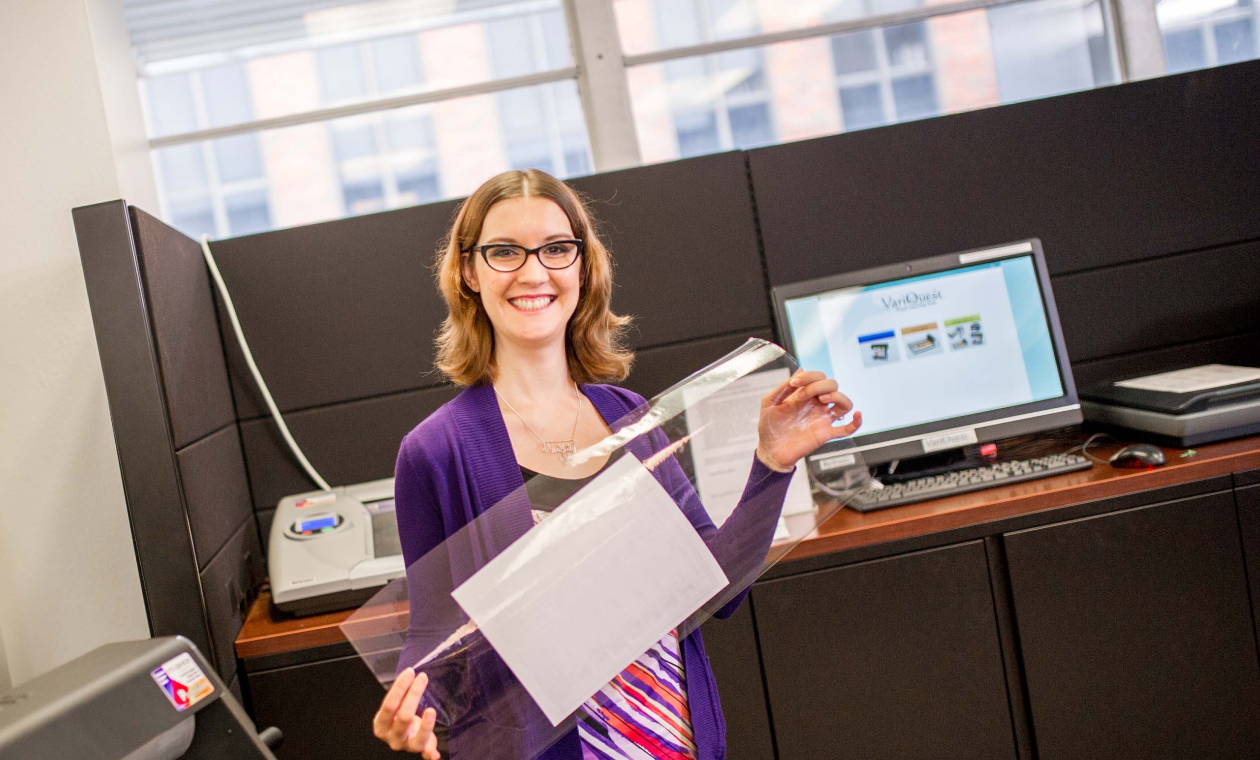 A female holding up a paper smiling.