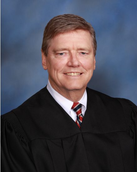 A headshot photo of a person wearing a judge's robe.