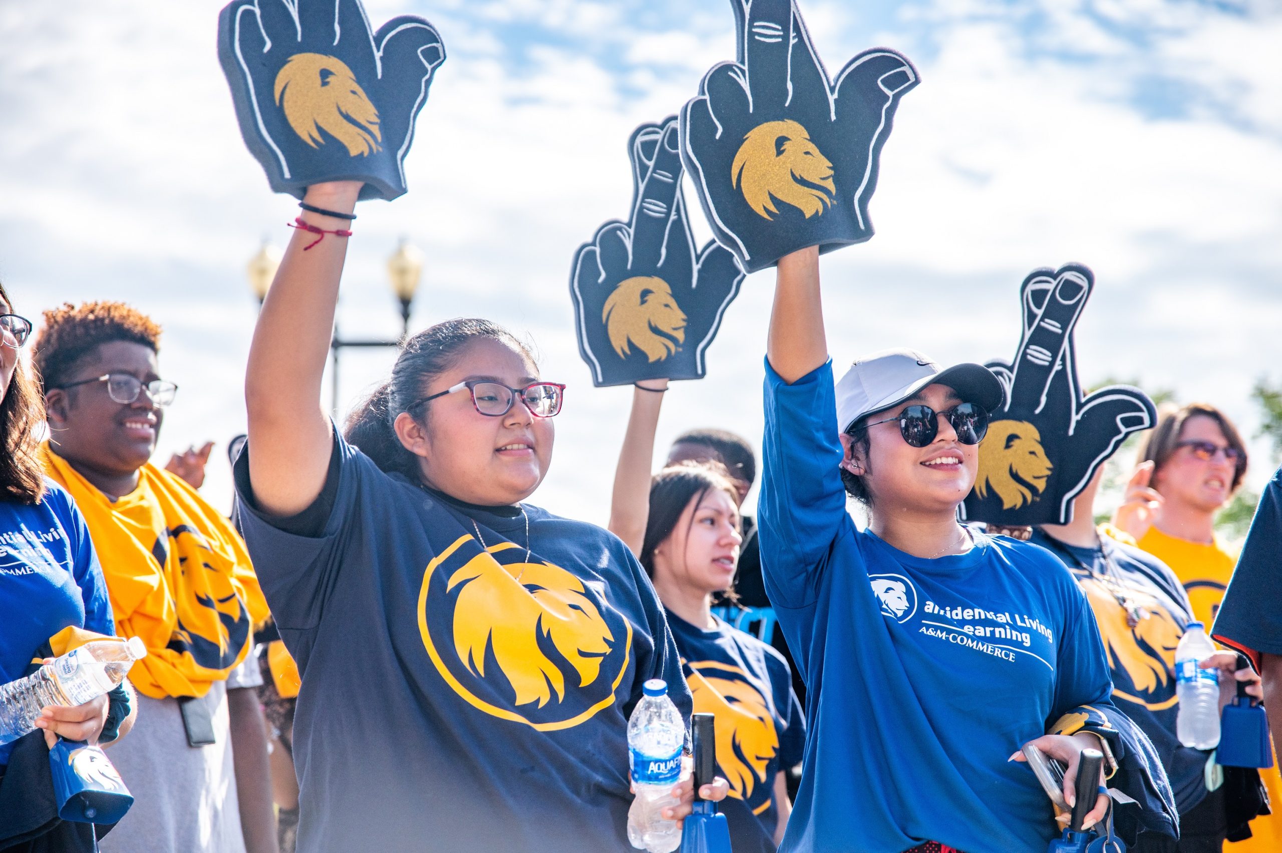 A group of student on the lion walk holding the lion hand sign.