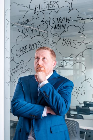 A person standing in front of a dry erase board with various notes written on it.