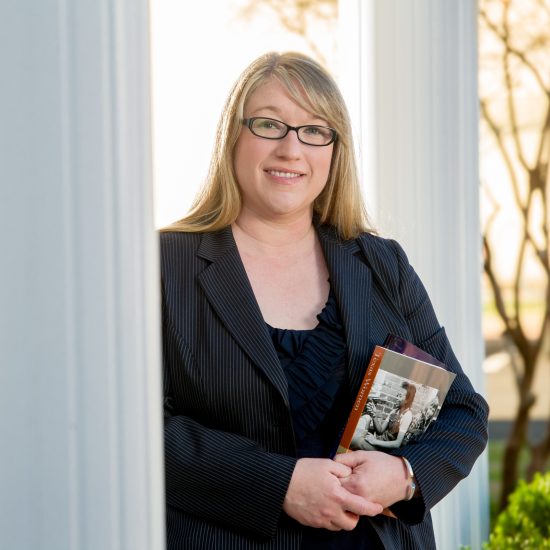 A person in professional attire holding books.