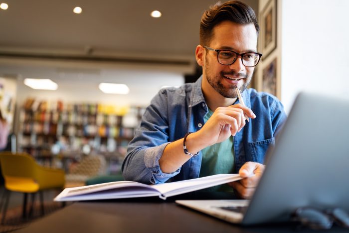 Smiling male student working and learning in a library