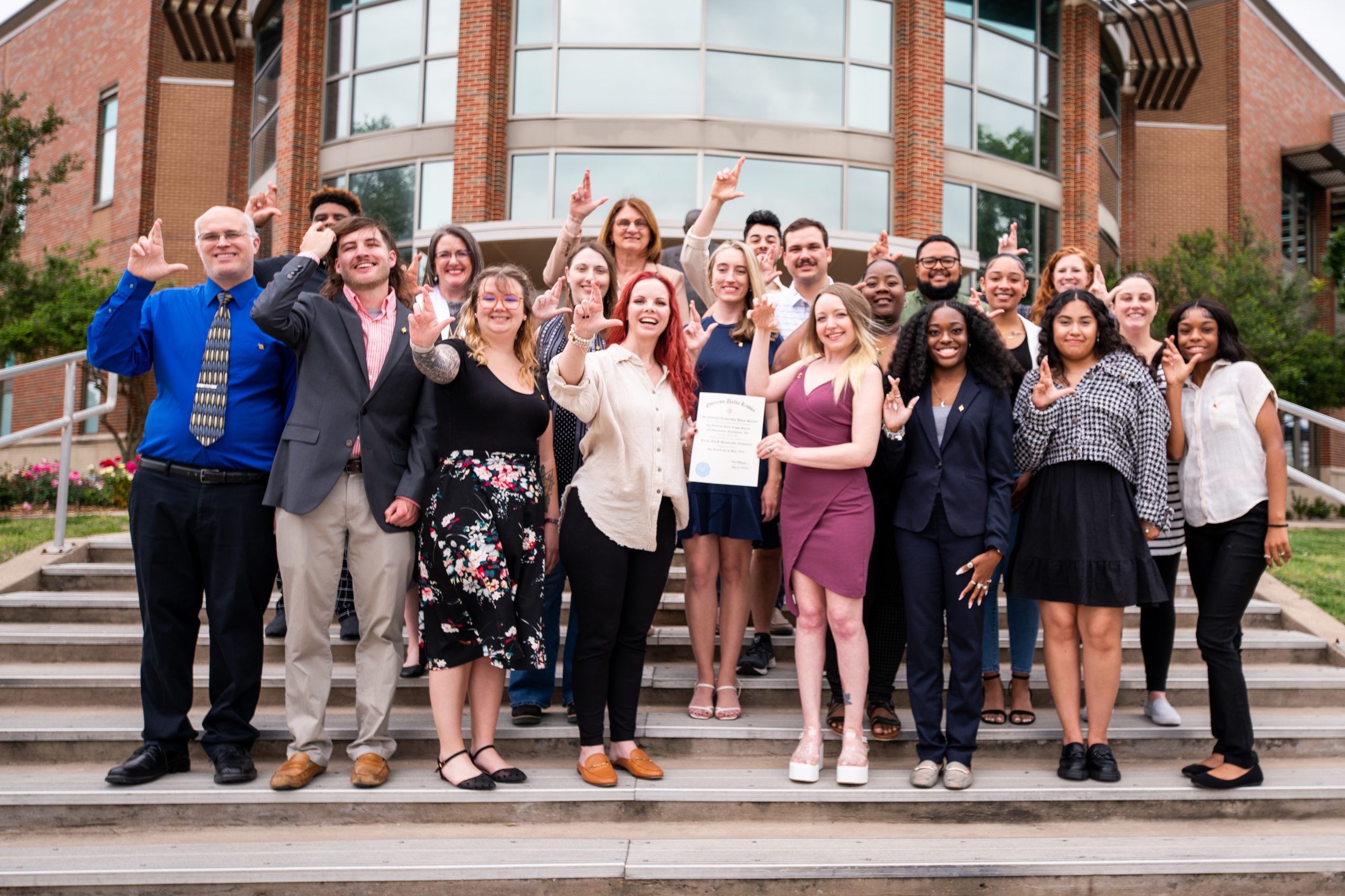 A group of females and males holding the Omicron Delta Kappa sign.