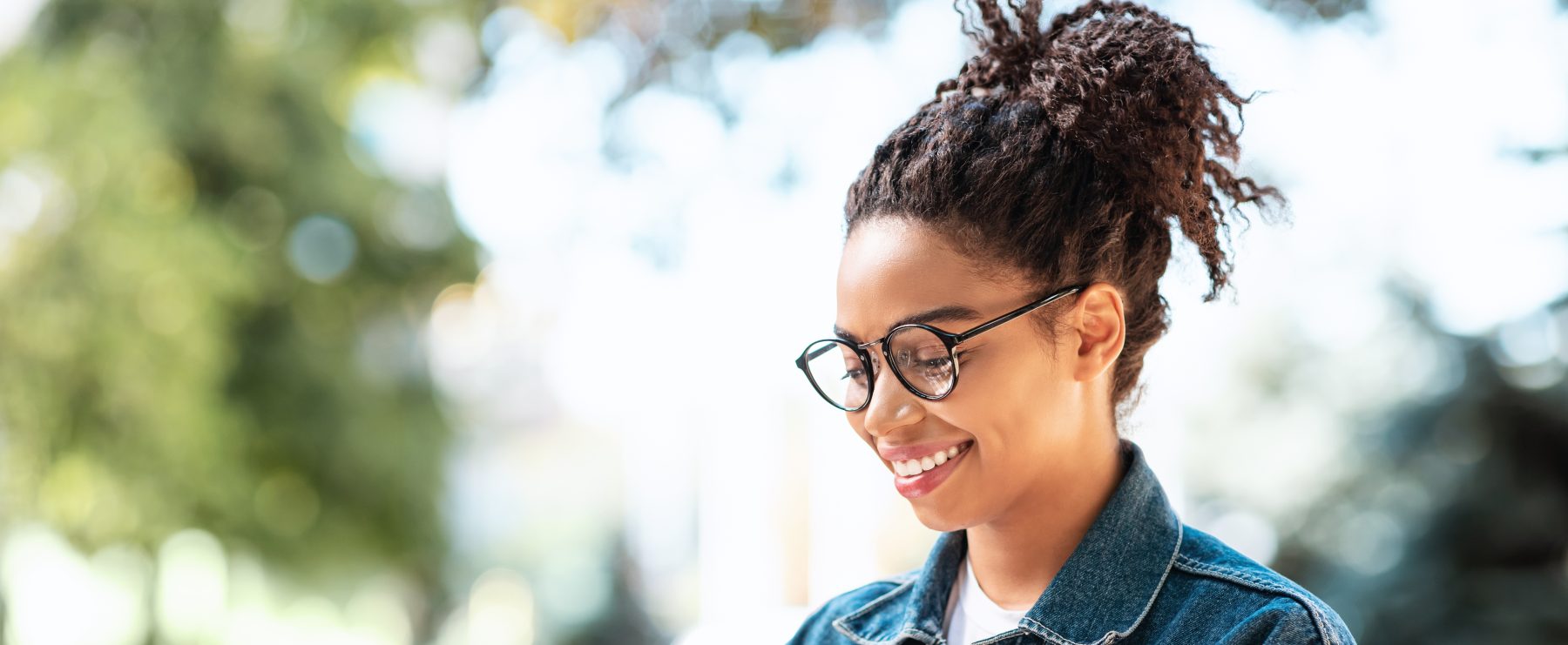 Cheerful Millennial Girl With Smartphone Using Mobile App Sitting outdoors.