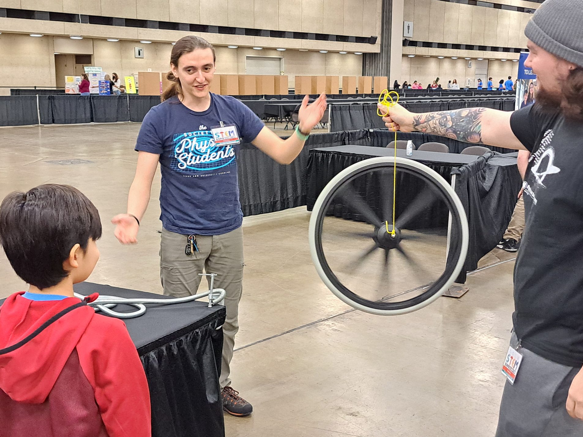 Two college students perform a science demonstration for a young boy.