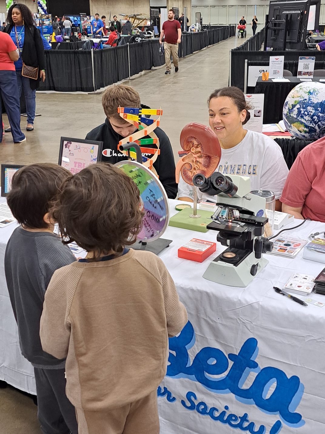 College students displaying various science demonstrations for school-age students.