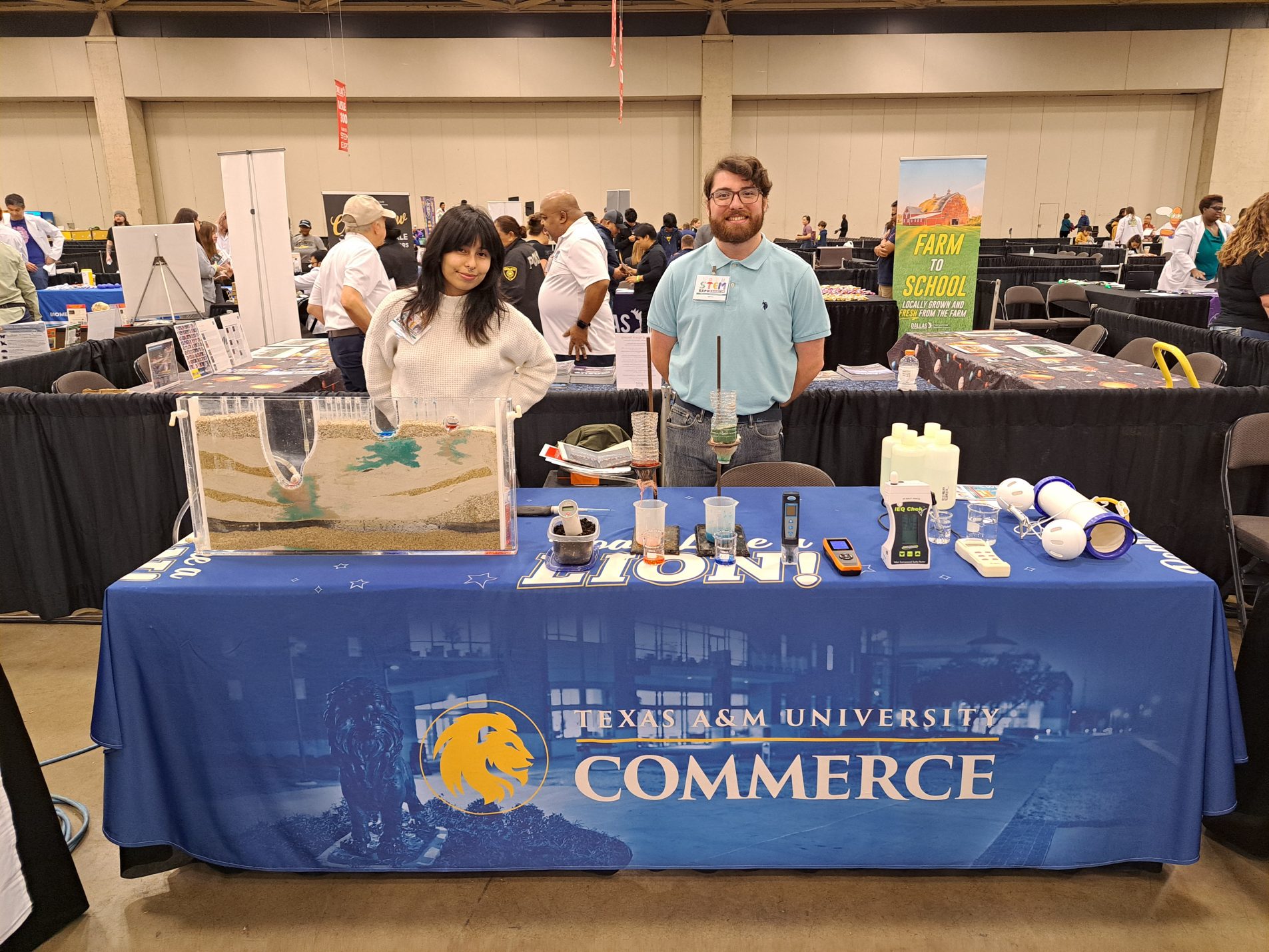 College students stand behind a table displaying various science demonstrations.