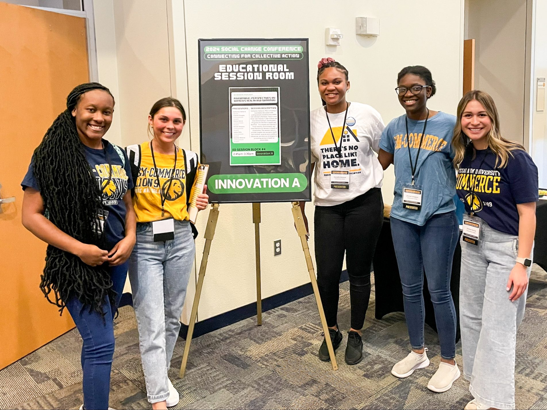 Five female students stand around a tripod holding a conference poster.