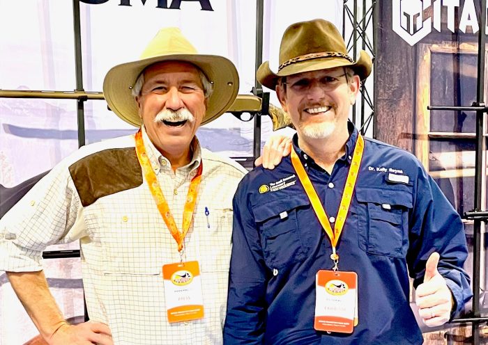 Two men wearing western hats pose together for a photo.
