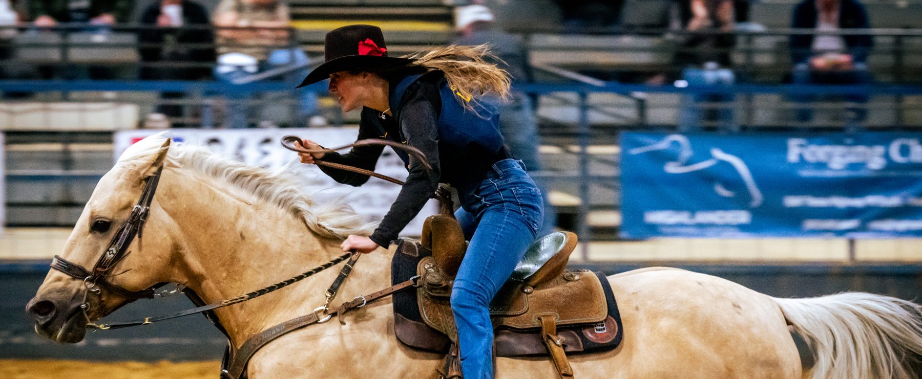 A person in western attire rides a horse during a rodeo competition.