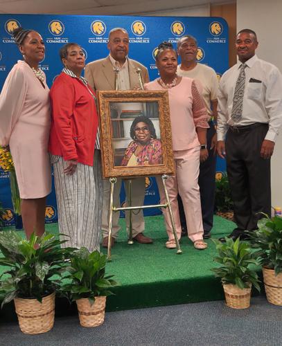 Six of Velma Waters' children, all grown adults, standing around a painted portrait of their mother