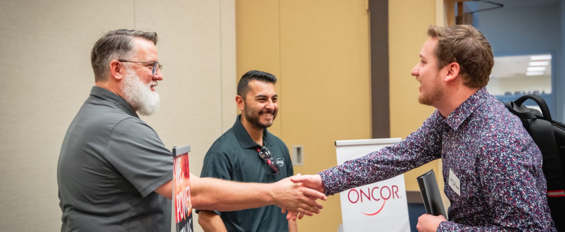 A student shakes hands with potential employers at a career fair.