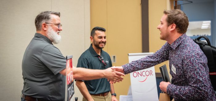 A student shakes hands with potential employers at a career fair.