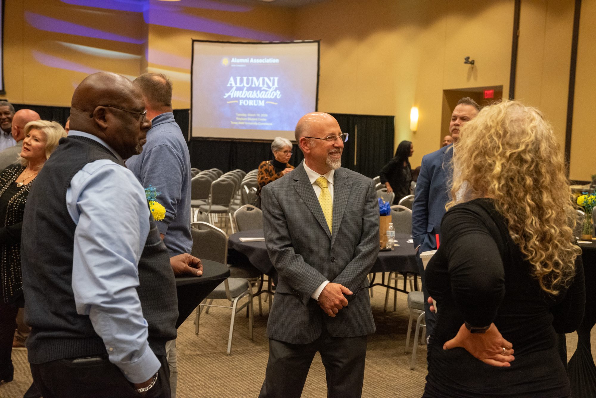 A circle of people smile and talk together at the Alumni Ambassador Forum.
