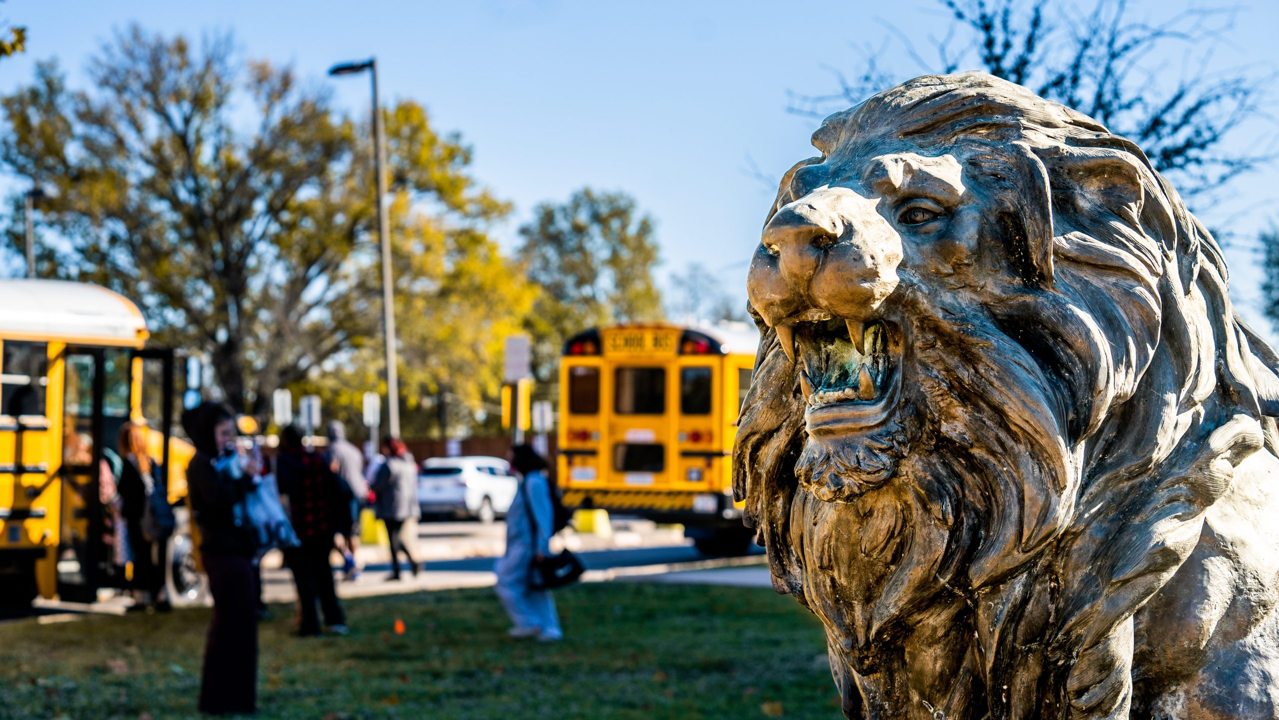 The lion statue with buses in the back ground. 