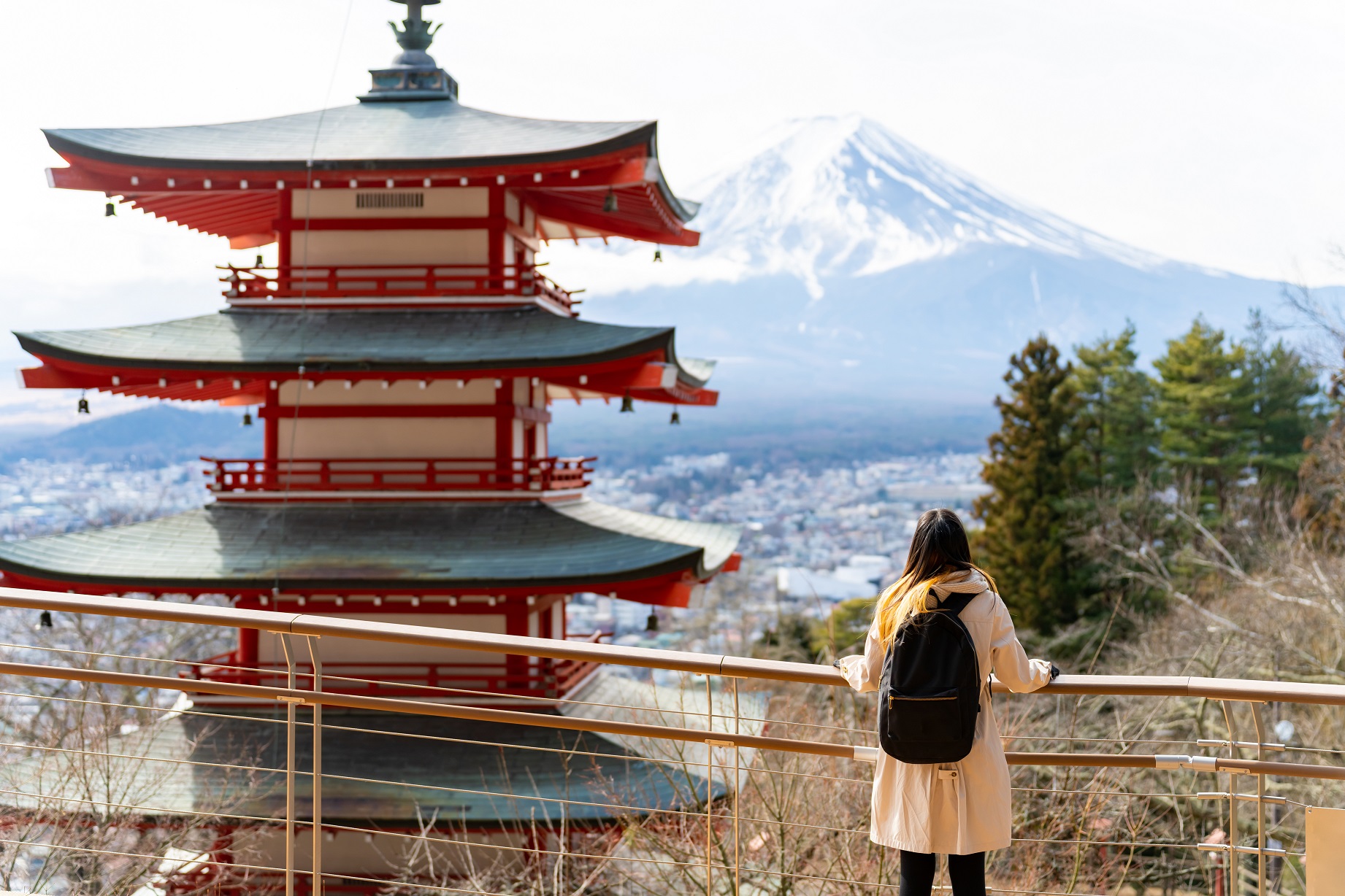 An asian lady standing in front of a asian temple with the mountain behind it.