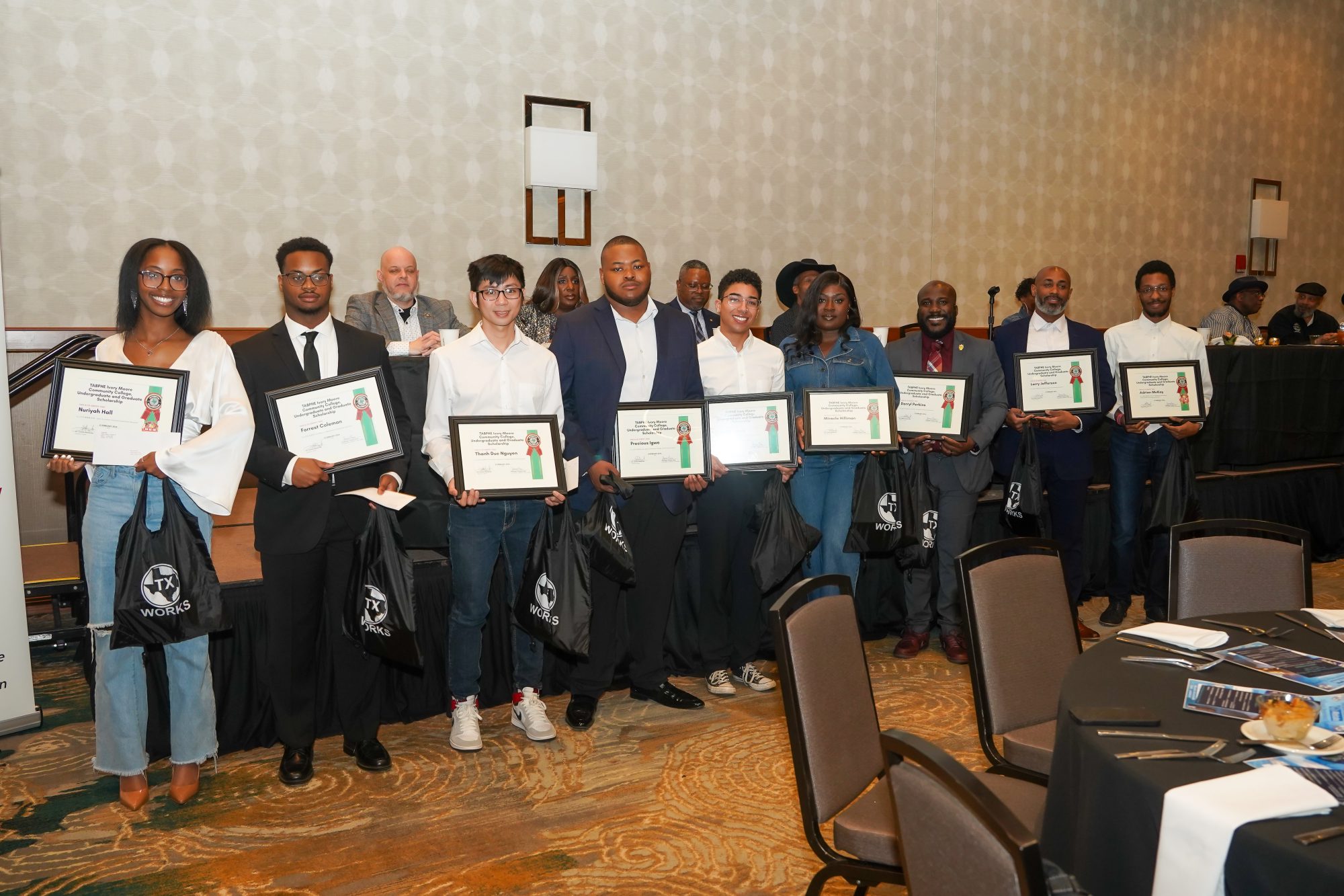 Nine students stand holding plaques and swag bags.