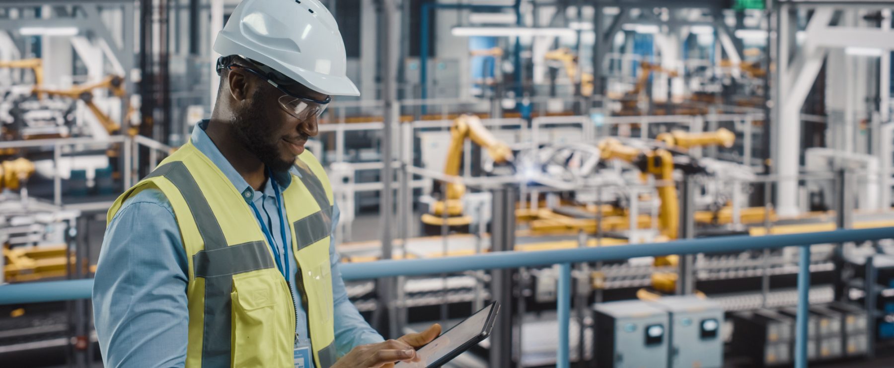 A male safety and health worker overseeing a factory assembly line.