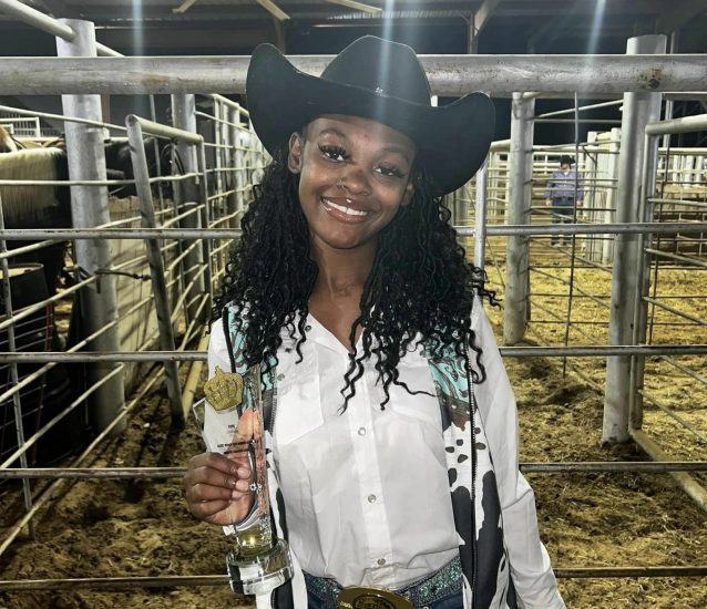 A person in western attire poses with a trophy.